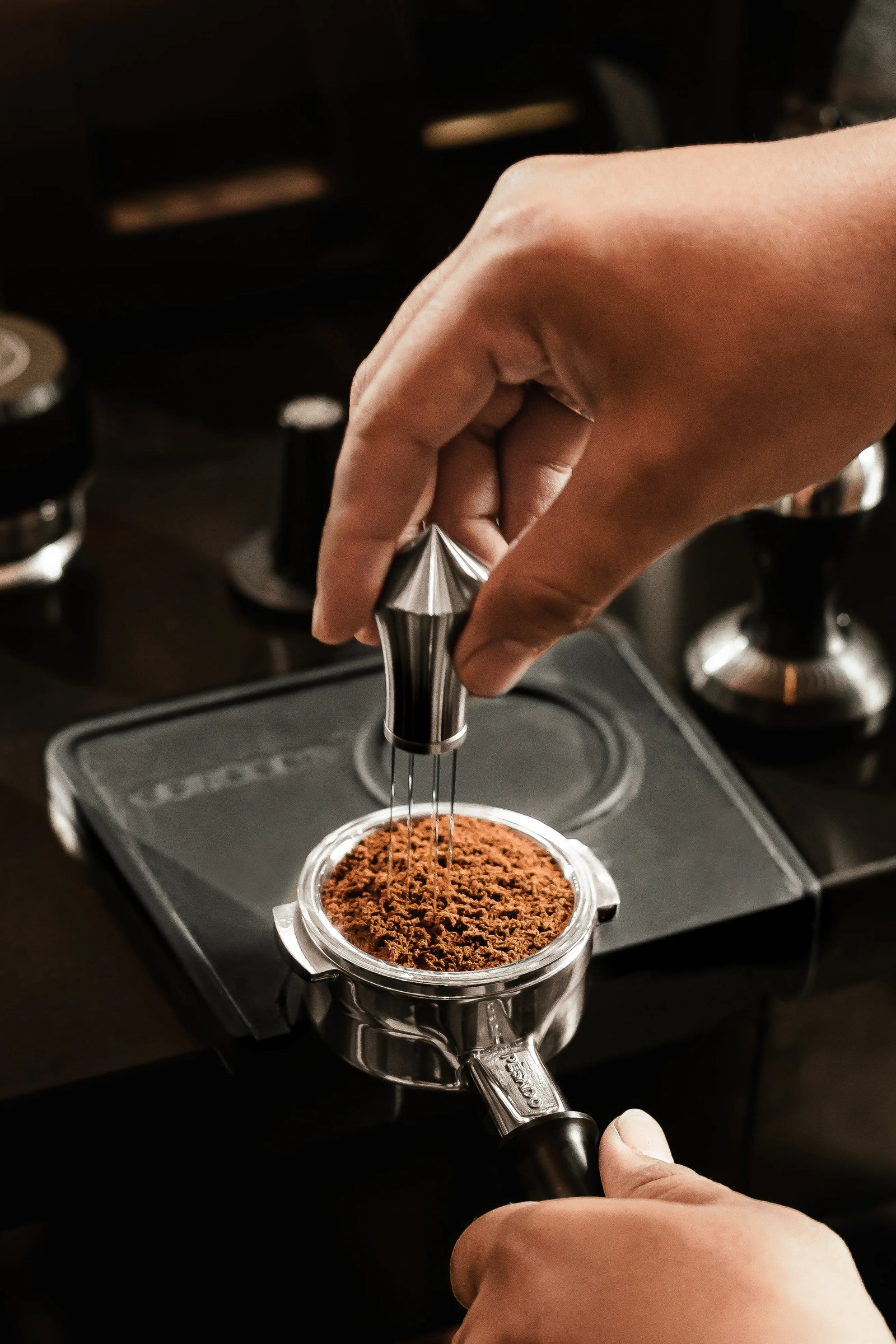 A Pesado clump clusher  being used in freshly ground coffee